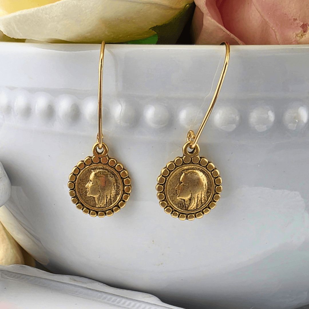 A pair of gold drop earrings with circular coin-style medallions featuring a Mary profile portrait, Sister Dulce Gift Shop, Shepherds Staff, Religious Store, Cypress Springs Mercedarian Prayer Center, Catholic,