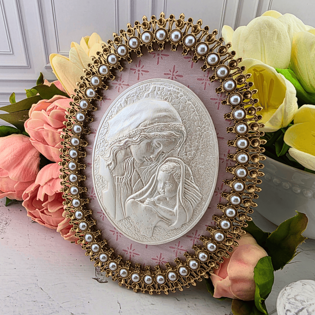An oval religious wall plaque featuring a white embossed depiction of the Virgin Mary holding the infant Jesus, surrounded by an ornate gold-tone frame adorned with faux pearls, Sister Dulce Gift Shop, Shepherds Staff, Religious Store, Cypress Springs Mercedarian Prayer Center, Catholic, new item, popular item, home decor, gift for her, young adult