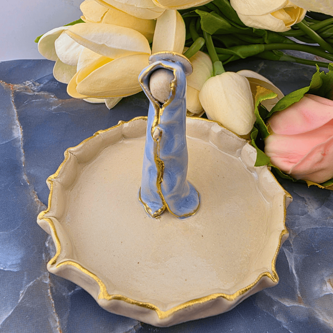 Sister Dulce Gift Shop, Shepherds Staff, Religious Store, Cypress Springs Mercedarian Prayer Center, Catholic, A ceramic dish with a scalloped rim, featuring a central blue boot-shaped holder with gold trim and a small white bead. 