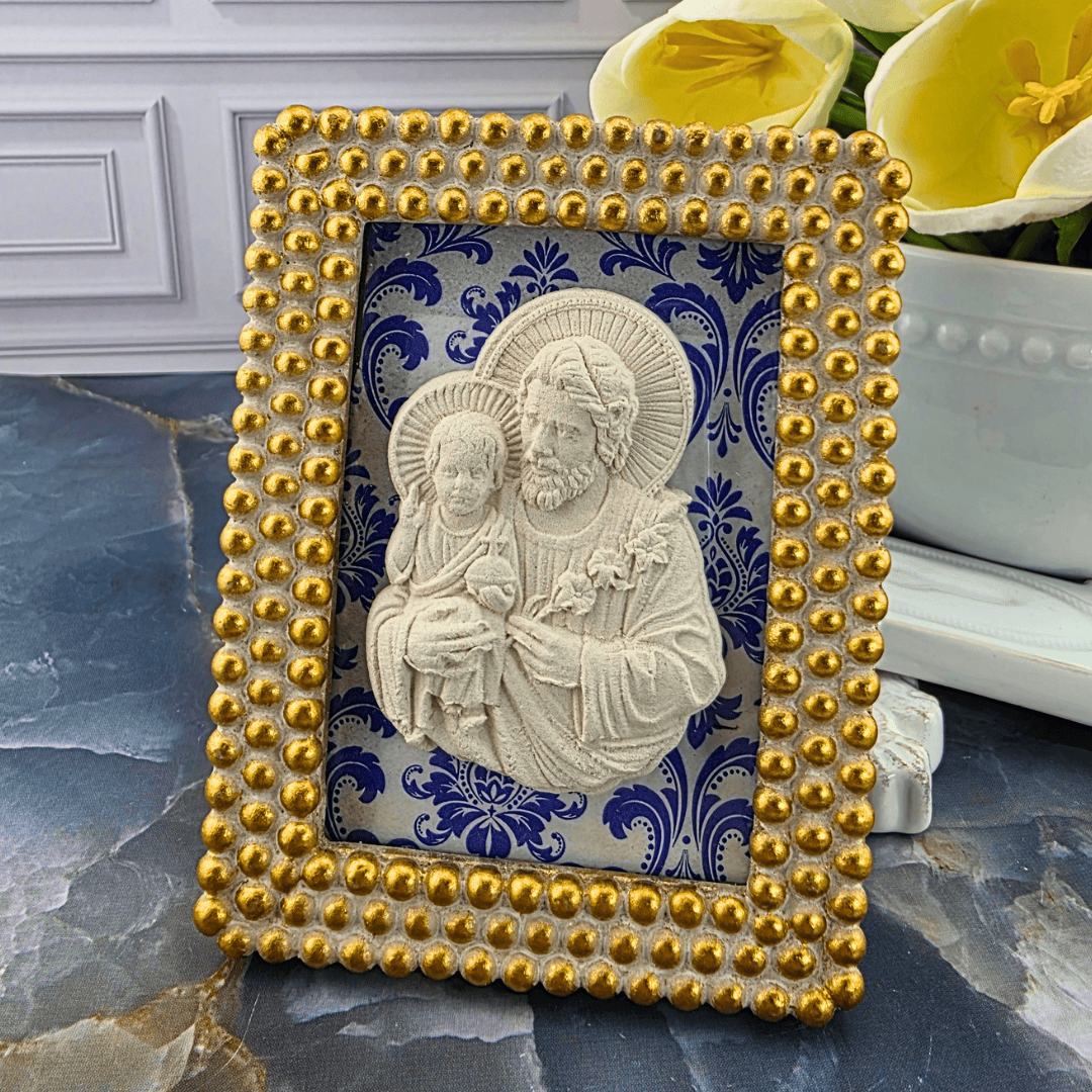 A decorative rectangular picture frame with a gold beaded border and a blue-and-white damask background, featuring a cream-colored relief of Jesus and the child. Sister Dulce Gift Shop, Shepherds Staff, Religious Store, Cypress Springs Mercedarian Prayer Center, Catholic, 