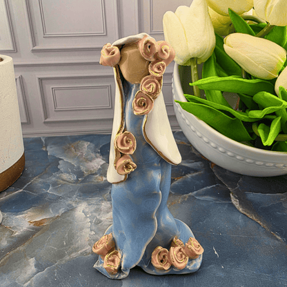 A decorative figurine of Mary in a flowing blue dress with pink roses along the neckline and hem, Sister Dulce Gift Shop, Shepherds Staff, Religious Store, Cypress Springs Mercedarian Prayer Center, Catholic, 