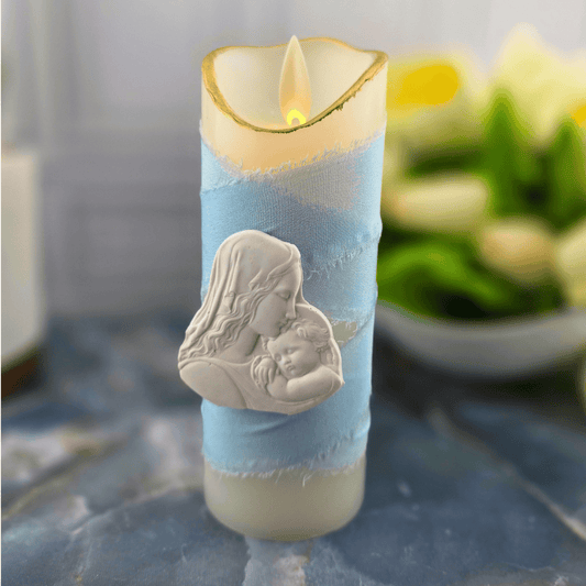 A decorative pillar candle with a light blue fabric wrap and a white relief of a mother and child, flameless candle, light blue madonna and child small, Sister Dulce Gift Shop, Shepherds Staff, Religious Store, Cypress Springs Mercedarian Prayer Center, Catholic, 