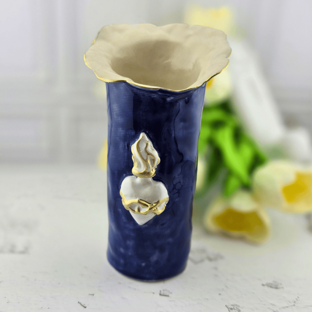 A ceramic flower vase with a deep navy blue body, a cream-colored flared rim with gold detailing, and a white and gold sacred heart ornament on the front, Sister Dulce Gift Shop, Shepherds Staff, Religious Store, Cypress Springs Mercedarian Prayer Center, Catholic, home decor, sacred treasures, new item, popular item