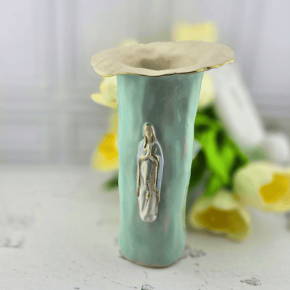 A handmade ceramic vase with a flared cream rim, a glossy light mint body, and a raised figure of the Virgin Mary on the front, Sister Dulce Gift Shop, Shepherds Staff, Religious Store, Cypress Springs Mercedarian Prayer Center, Catholic, sacred treasures, new item, popular item, home decor