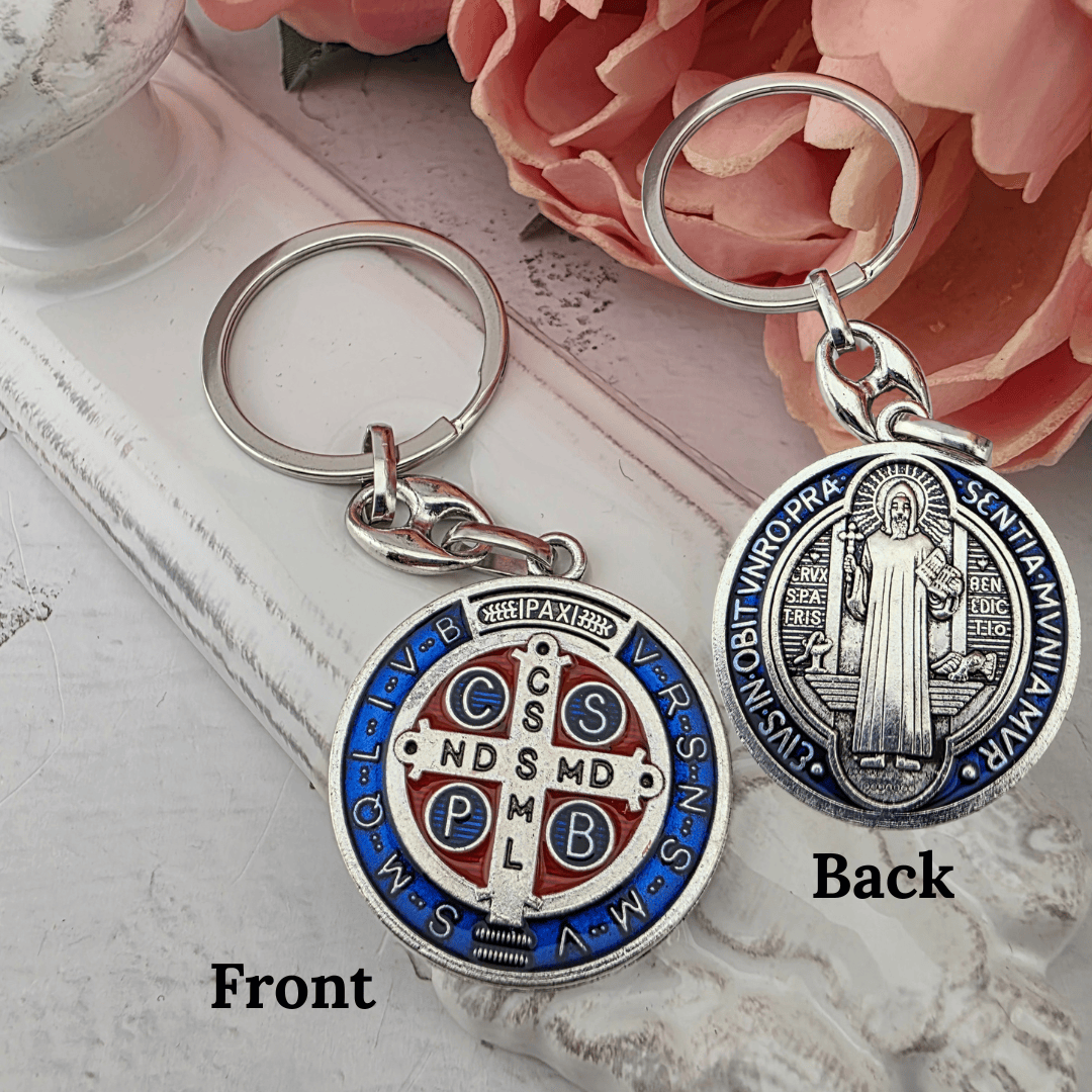Two silver-tone Saint Benedict keychain, One keychain displays the front of the medallion with blue, red, and white enamel details, and the other shows the back with saint benedict, new item, gift for him, new driver